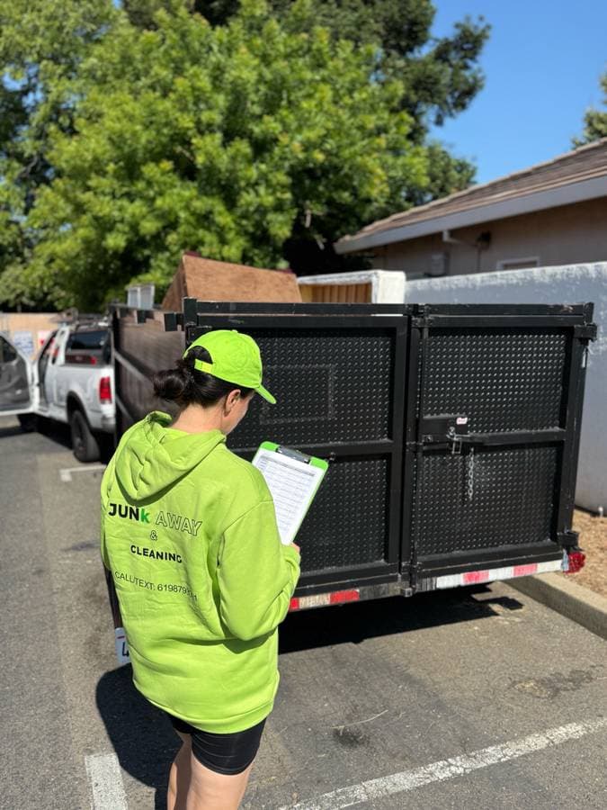 Owner of Sacramento junk removal company reviewing checklist beside trailer before junk hauling job